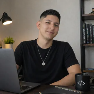 Portrait of Oscar Marín at his desk, in front of a laptop, with software engineering books in the background.